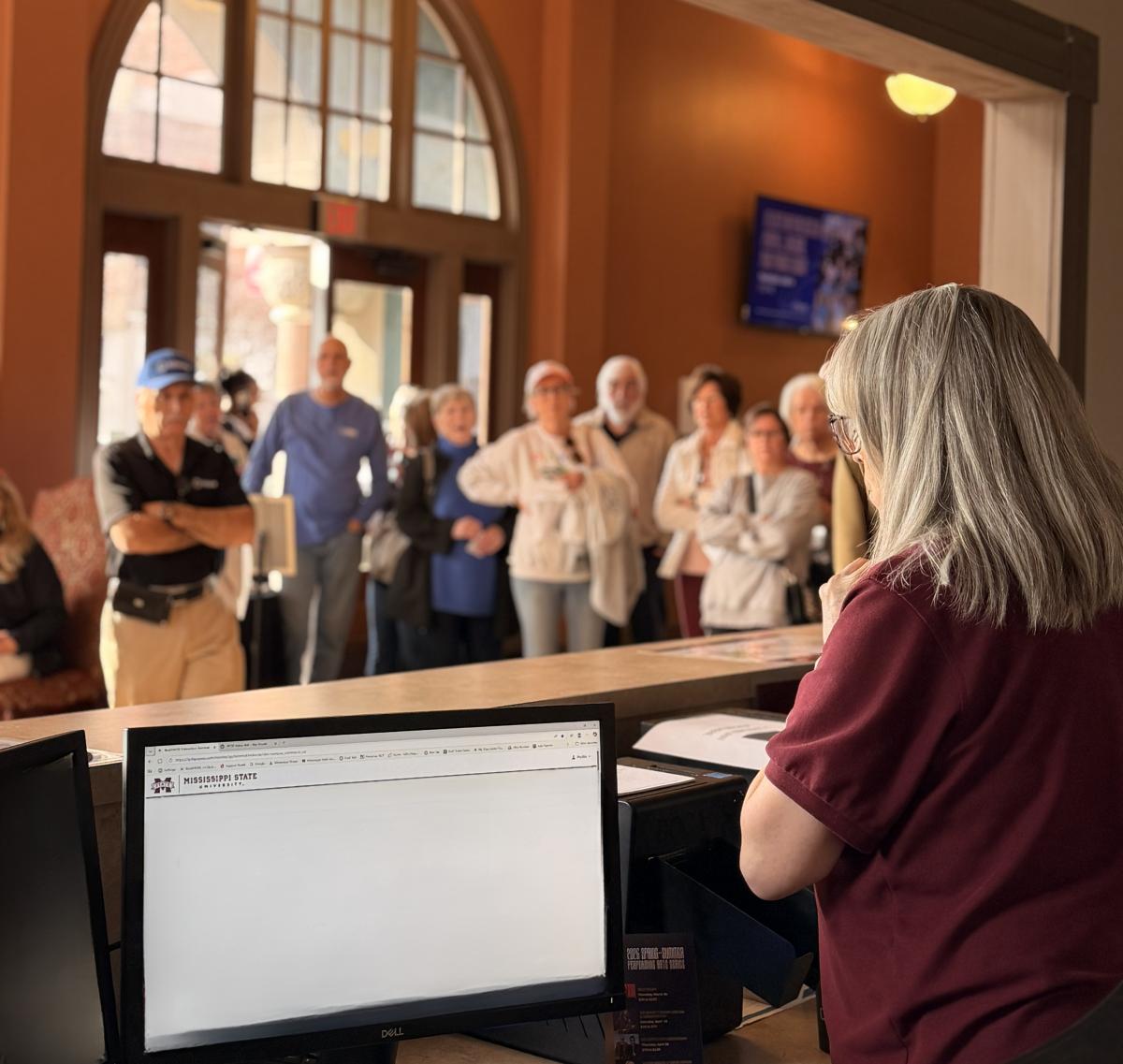 A staff member assisting customers at the theater box office ticket window.