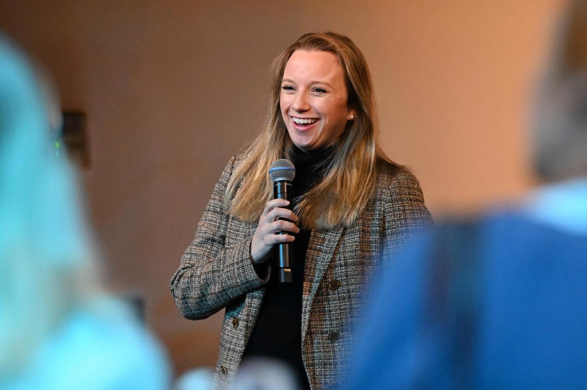 Director Morgan smiling and speaking into a microphone during an event.
