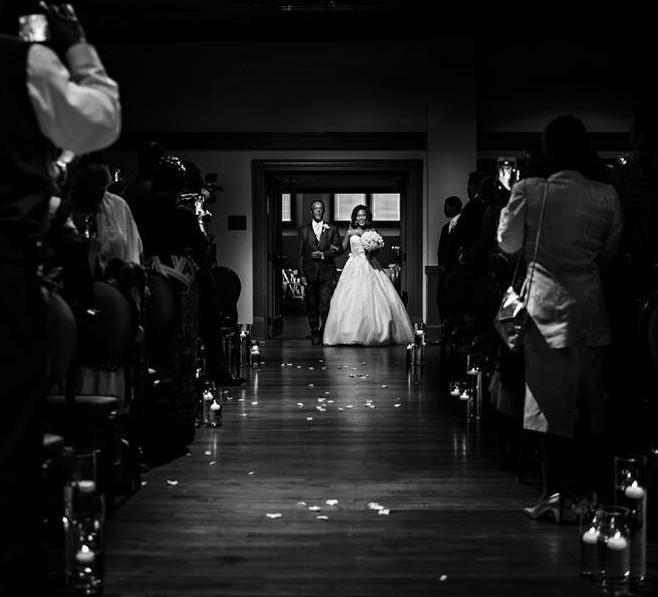A bride being walked down the aisle by her father during a wedding ceremony in the intimate Studio Theater at the MSU Riley Center.